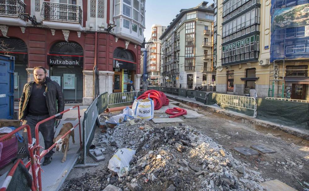 Un ciudadano pasea a su perro por una de las pasarelas dispuestas por el Ayuntamiento, junto a las obras de la calle Isabel II, en Santander.