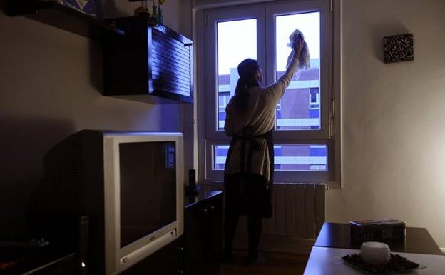 Una mujer realiza labores domésticas en una vivienda. 