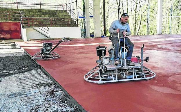 Un obrero da los últimos retoques a la pista deportiva de Mirones, que también cuenta con una cubierta y que estará lista en breve para el disfrute de los niños