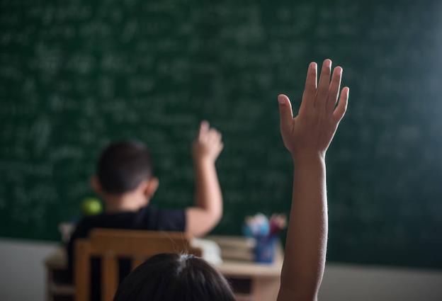 Pequeños levantan la mano en clase.