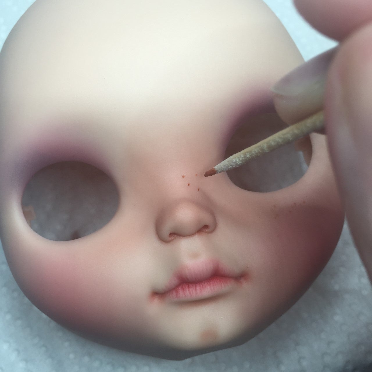 Pintando pecas en una Blythe después de realizar el maquillaje.