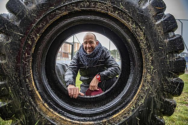 Simon Hafoka posa con una rueda de tractor, uno de los elementos que se utilizan para entrenar la fuerza en el Bathco.