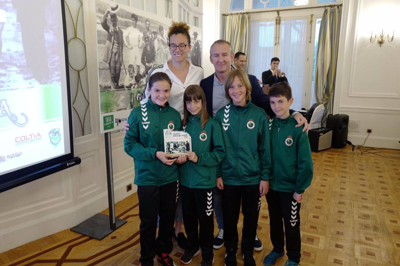 Los niños de la Academia del Racing, Paula, Carla, Alejandro y Daniel posan con su trofeo junto a la jugadora de baloncesto Laura Nicholls y el director de la Academia del Racing, César Anievas.