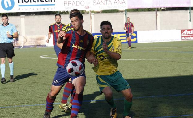 El jugador taniego Jorge pugna por el balón con un rival.