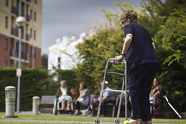 Una mujer camina por el jardín de una residencia. :: javier cotera