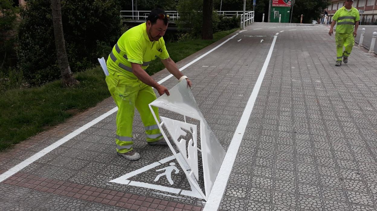 Un operario trabaja en la señalización de uno de los tramos del carril en el que los peatones y ciclistas compartirán la acera.