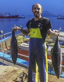 Imagen secundaria 2 - Arriba, un comprador observa los bonitos en la lonja. Debajo, Yulen, marinero del 'Beti Gure Iskander', embarcación con base en Santurce, muestra los bonitos descargados en Santoña.