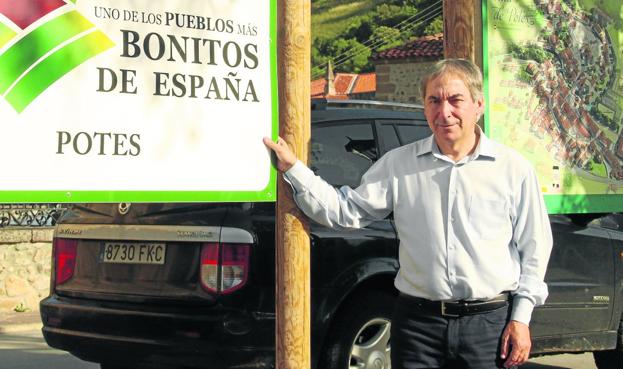 Javier Gómez, junto a uno de los carteles en los que se reconoce el nombramiento de Potes como uno de los pueblos más bonitos.