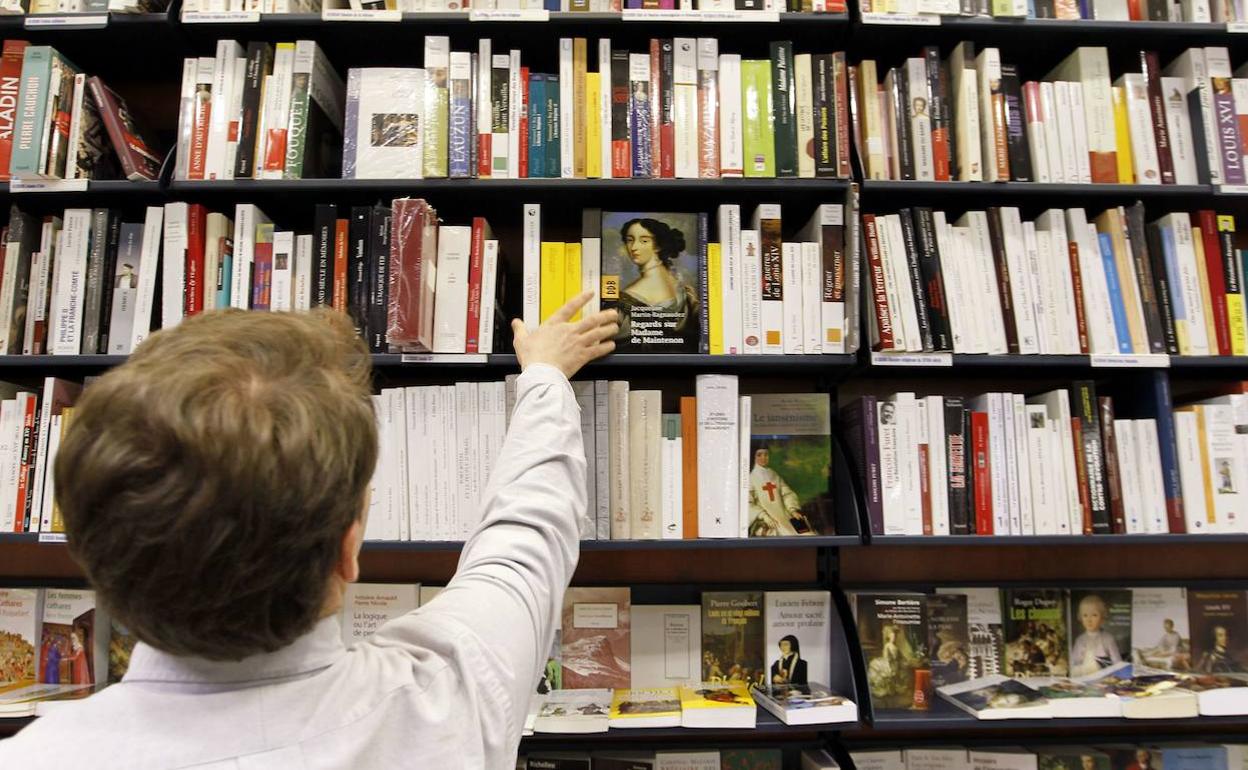 Una empleada de una librería coloca un libro. 