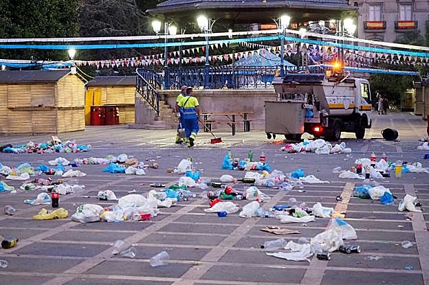Dos operarios del servicio de limpieza recogen los restos de botellón en la plaza de Pombo. 