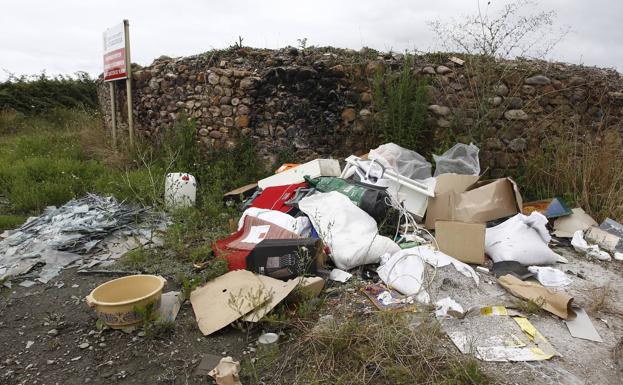 Imagen principal - 1. Basura acumulada en el límite con Santiago de Cartes. | 2. Colchones tirados frente al Punto Limpio de Torrelavega.