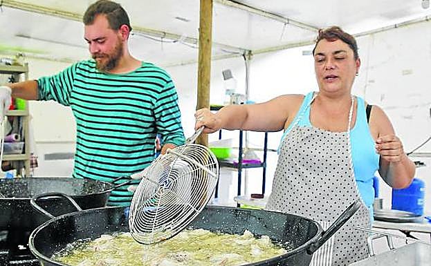Imagen principal - A los cocineros les toca freír alitas de pollo para 120 personas. De primero han servido ensalada de pasta.