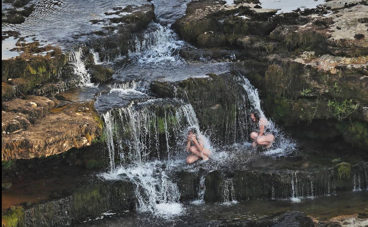 Dos jóvenes se refrescan en las cascadas del Bolao, en Cóbreces.