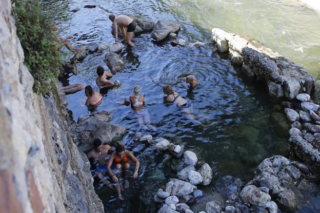 Un grupo de bañistas disfruta de las pozas termales donde el agua brota a casi sesenta grados centígrados.