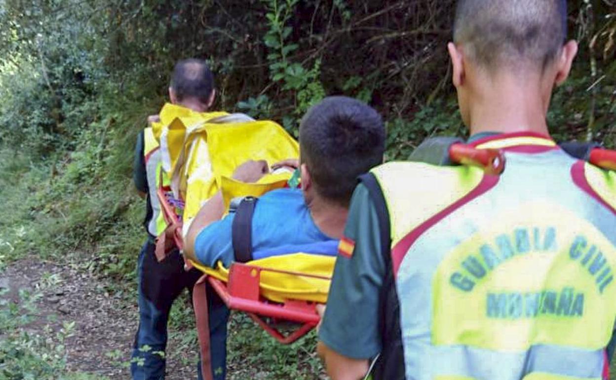 Dos agentes del Greim portean a uno de los montañeros heridos. 