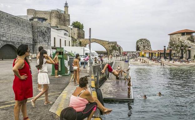 Un joven salta al agua ante la mirada de paseantes y bañistas en el entorno de San Guillén, en Castro Urdiales. : 