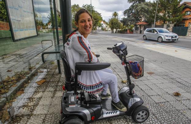 Lola González-Pinto espera el autobús sobre su moto adaptada. 