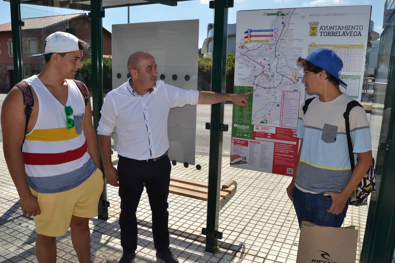 El alcalde Agustín Moleda, con dos estudiantes, en la parada del autobús.