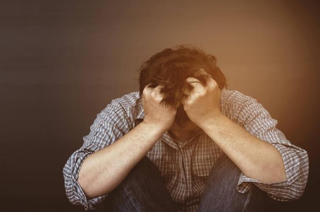 Un hombre en actitud triste, con el gesto común de llevarse las manos a la cabeza.