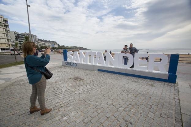 Una familia posa en el cartel colocado en la segunda playa de El Sardinero.