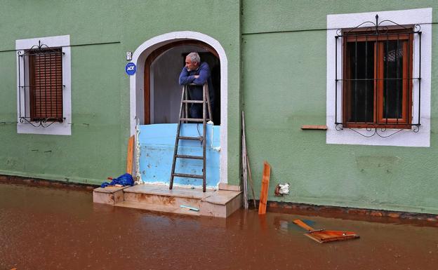 Imagen. Un vecino protege su vivienda de las lluvias en Villanueva de la Peña.