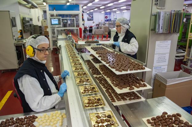 Dos trabajadoras supervisan, dotadas de las máximas medidas higiénicas, la producción de bombones en la planta de confitería. 