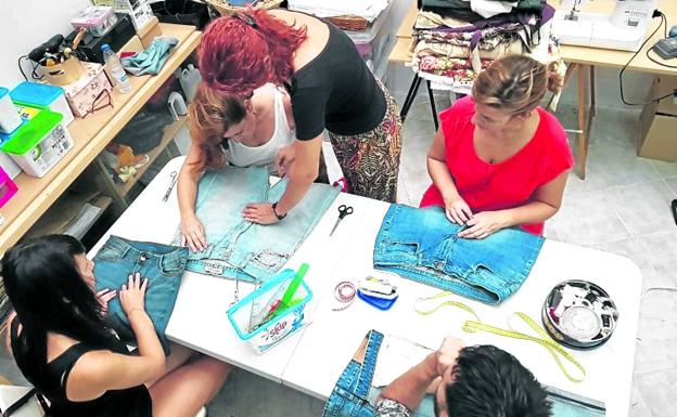 Imagen principal - Marina López, de pie, controla la elaboración de prendas en su taller.