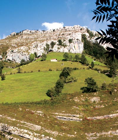 Escarpado paisaje de San Roque de Riomiera; al fondo, una cabaña pasiega.