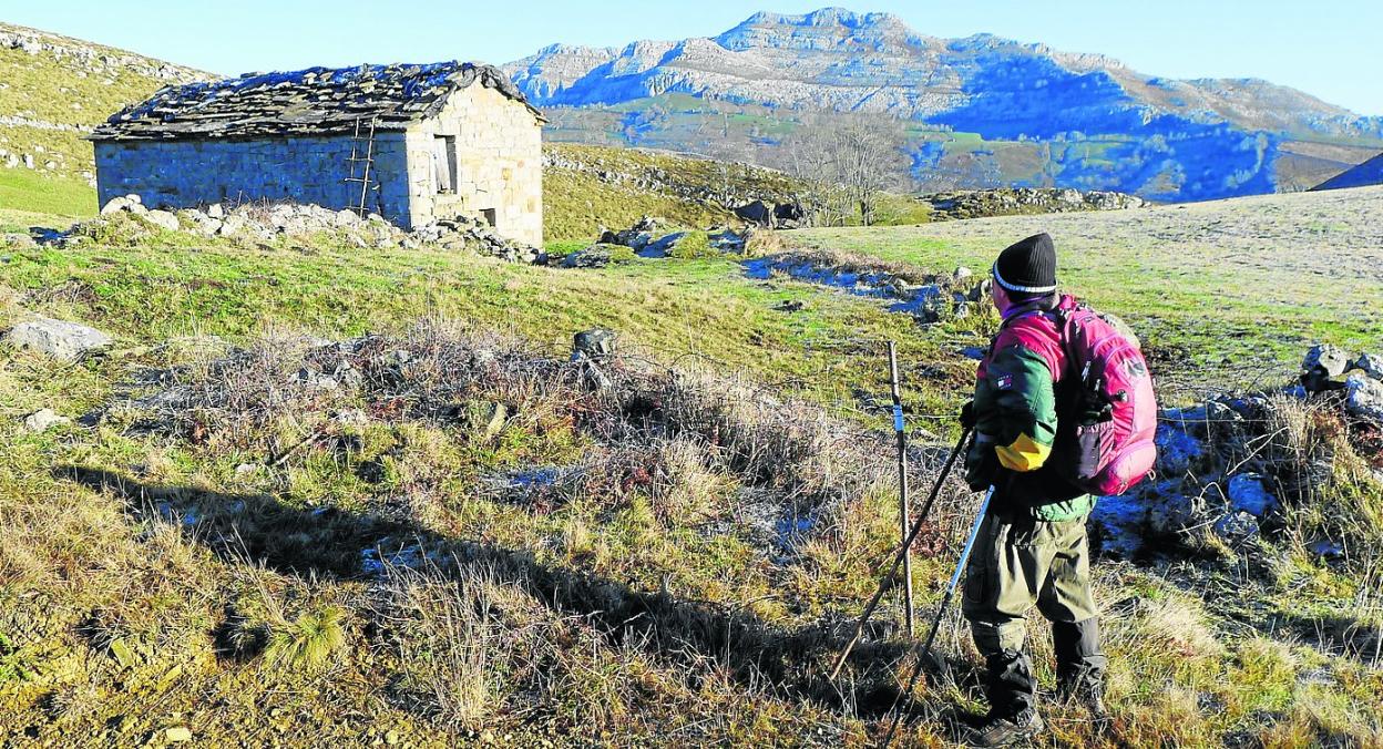 Un excursionista observa una de las cabañas pasiegas existentes a lo largo de la ruta.