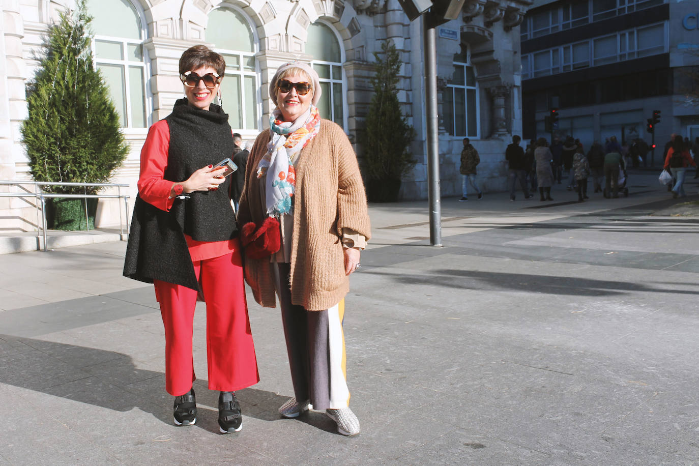 'Total look' blusa y 'palazzo' rojo con jersey tipo capa de cuello alto negro, con zapatillas deportivas y accesorios en rojo. Junto a cárdigan caqui, y pantalón 'palazzo' combinado en negro amarillo y blanco, lleva un bolso de pelo rojo.