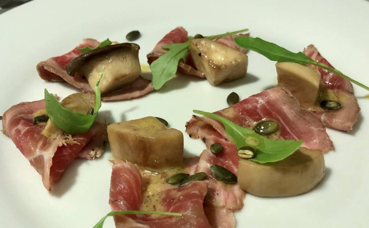 Presentación de la presa con setas en escabeche y hojas de rúcula. :