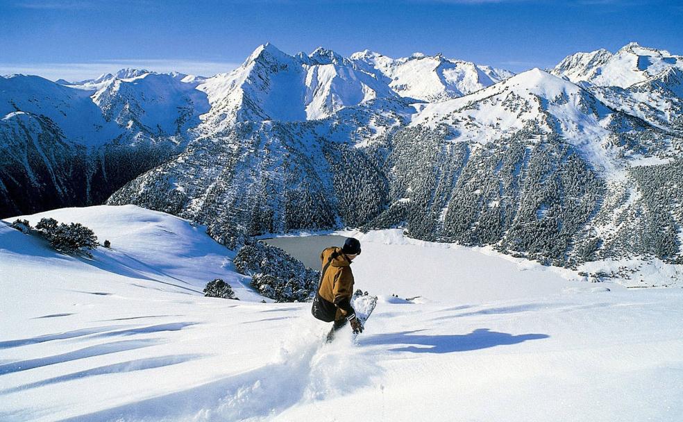 Un snowboarder desciende hacia un lago en el Pirineo Francés