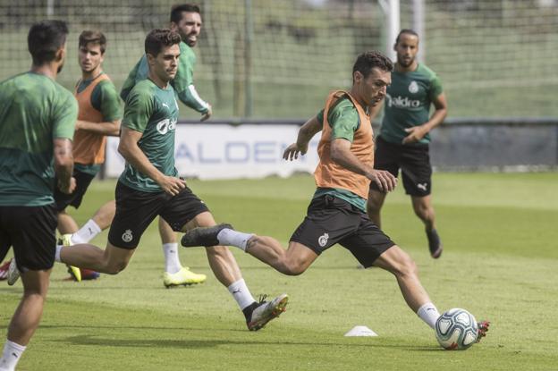 David Barral golpea el balón en un entrenamiento, perseguido por Óscar Gil. :: javier cotera