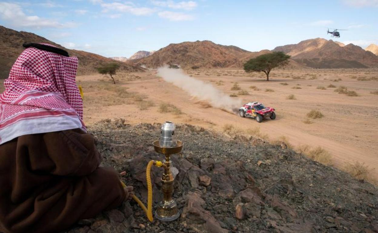 Un hombre saudí observa el coche Mini que pilota el español Carlos Sainz durante la cuarta etapa del rally Dakar.