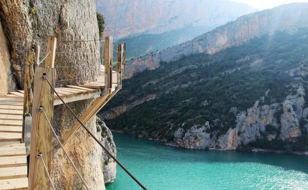 Pasarela de Montfalcó (Aragón). Esta es una de las rutas más impresionantes que podrás hacer en Aragón por sus vistas de vértigo, pero también porque se trata de una de las rutas más fotogénicas. Su itinerario parte desde el albergue de Montfalcó, desde el que se puede ir andando hasta el comienzo de las pasarelas y por el que también nos adentraremos en un paisaje de enorme belleza que recorre la cola del embalse de Canelles. Una vez hayamos llegado a la pasarela, toca 'tragar saliva' y subir más de 80 m de pared rocosa por unos cómodos tramos de escalera. Su ascenso no es difícil, pero sí impactante sobre todo por el paisaje tan espectacular con el que nos encontraremos desde lo alto.