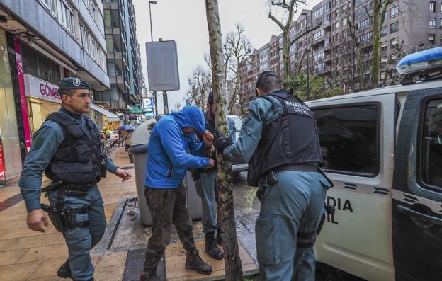 Tres efectivos de la Guardia Civil introducen al detenido en el coche patrulla. 