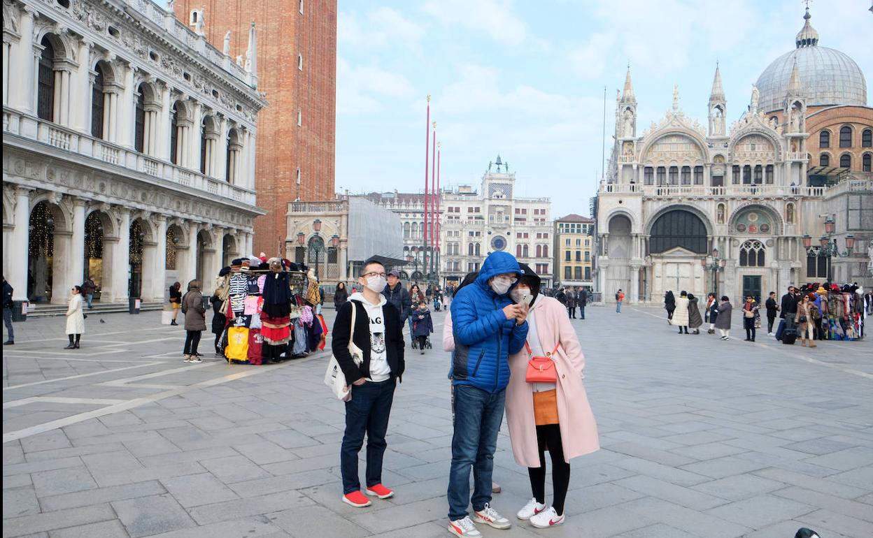 Unos turistas llevan máscaras para protegerse contra el coronavirus en la plaza de San Marcos de Venecia (Italia).