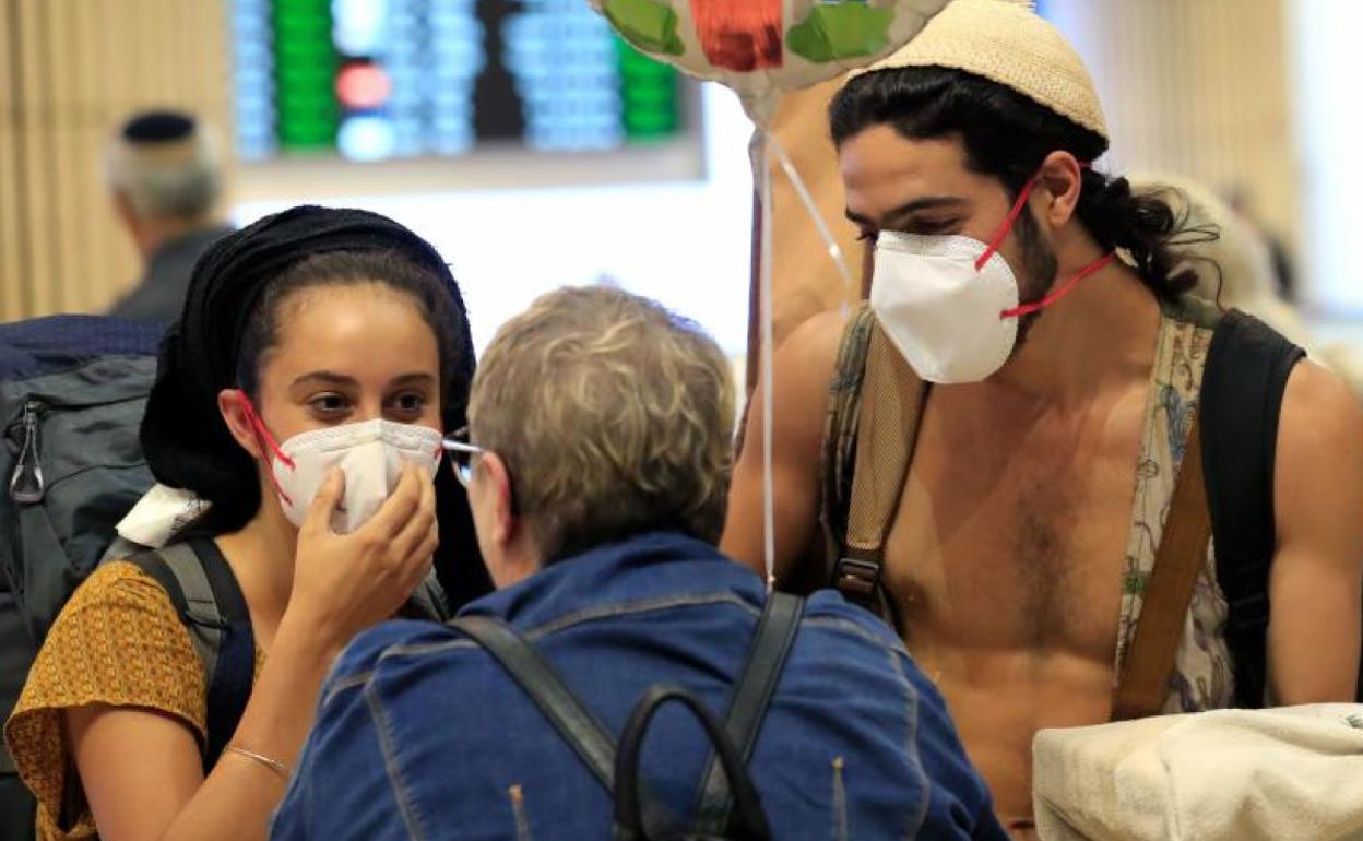 Dos jovenes con mascarillas son recibidos a su llegada al aeropuerto internacional de Ben Gurion, en Tel Aviv. 