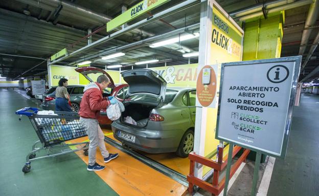 Dos clientes colocan sus compras en sus coches en los puntos habilitados. 