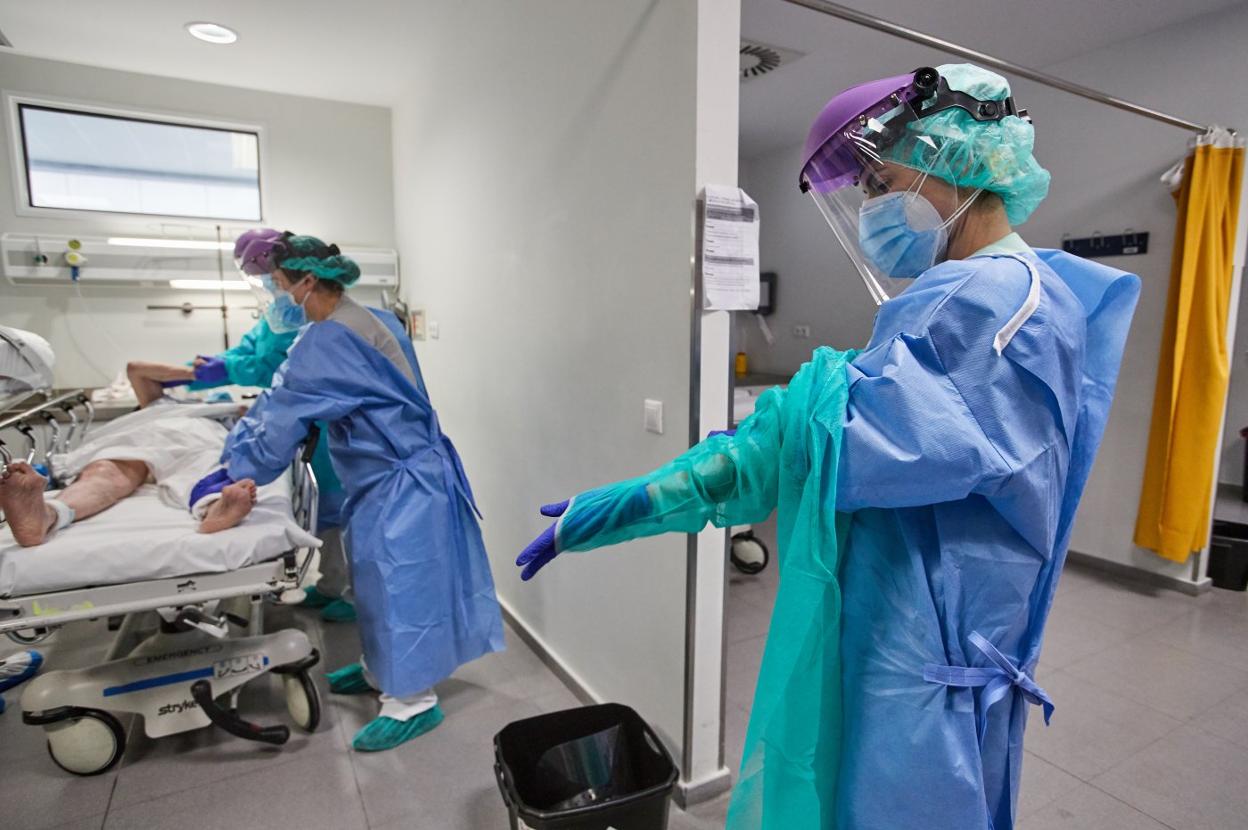 Personal sanitario, con los trajes de protección, atienden a un paciente en la unidad de Covid-19 de Urgencias de Valdecilla. 