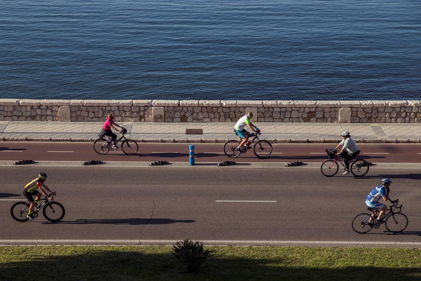 Unas personas en bicicletas por el paseo de la Malagueta de Málaga. 