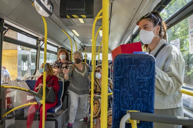 Los pasajeros usan mascarillas y ocupan la mitad de los asientos del autobús. 