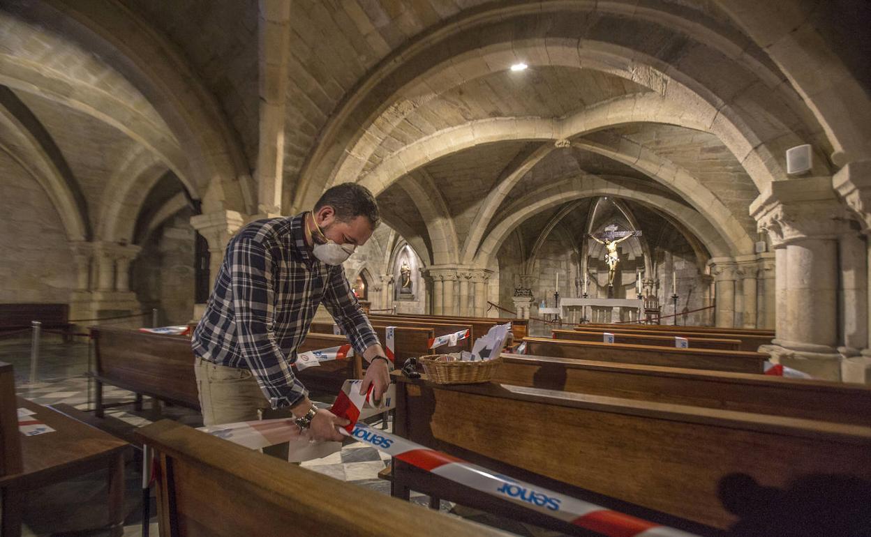 Un hombre coloca cintas para indicar dónde no deben sentarse los feligreses en la Iglesia del Cristo. 