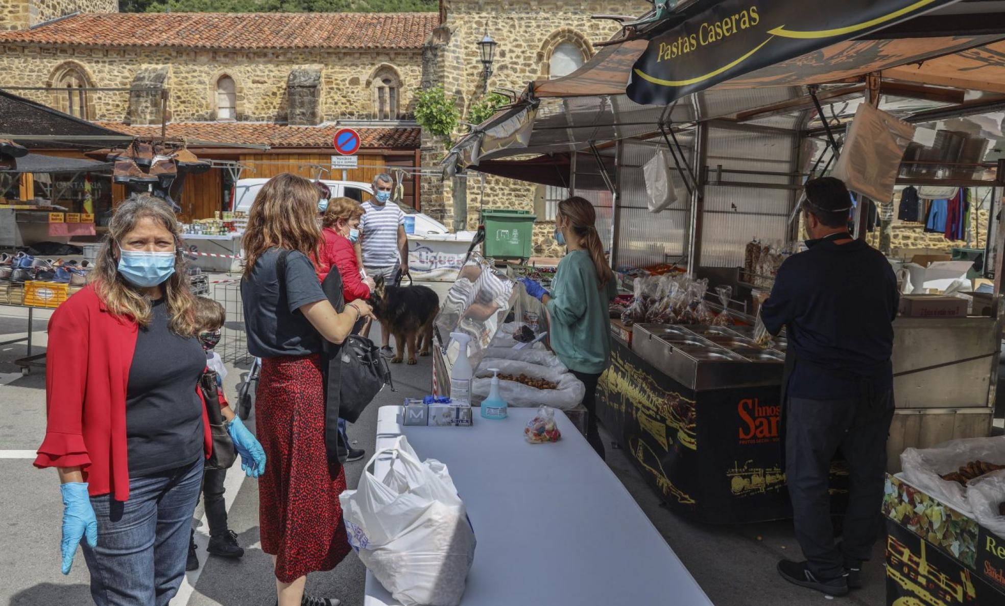 Un grupo de clientes hace cola ante un puesto de venta, ayer, en el mercadillo de Potes. pedro álvarez