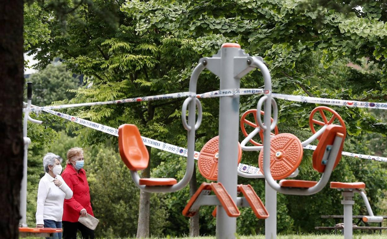 Dos mujeres pasean por un parque. 