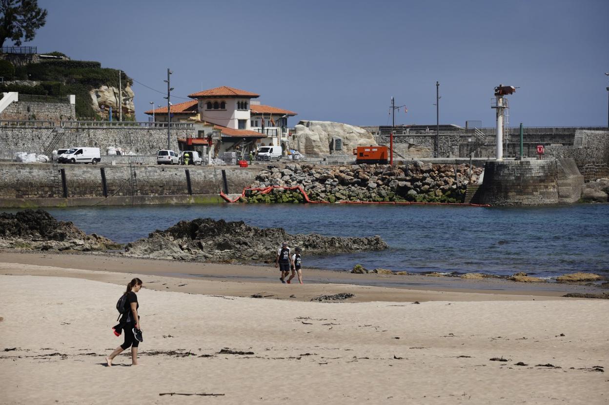 Varias personas pasean por la playa de Comillas.