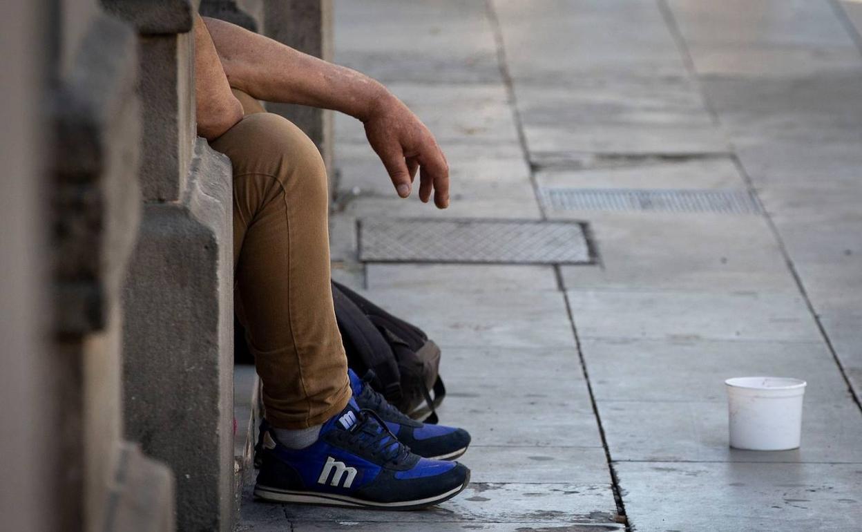 Un hombre pide limosna en una calle de una ciudad española.