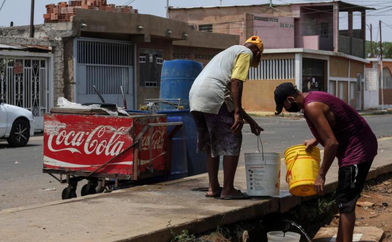 Dos personas recogen agua en Venezuela durante la pandemia de coronavirus 