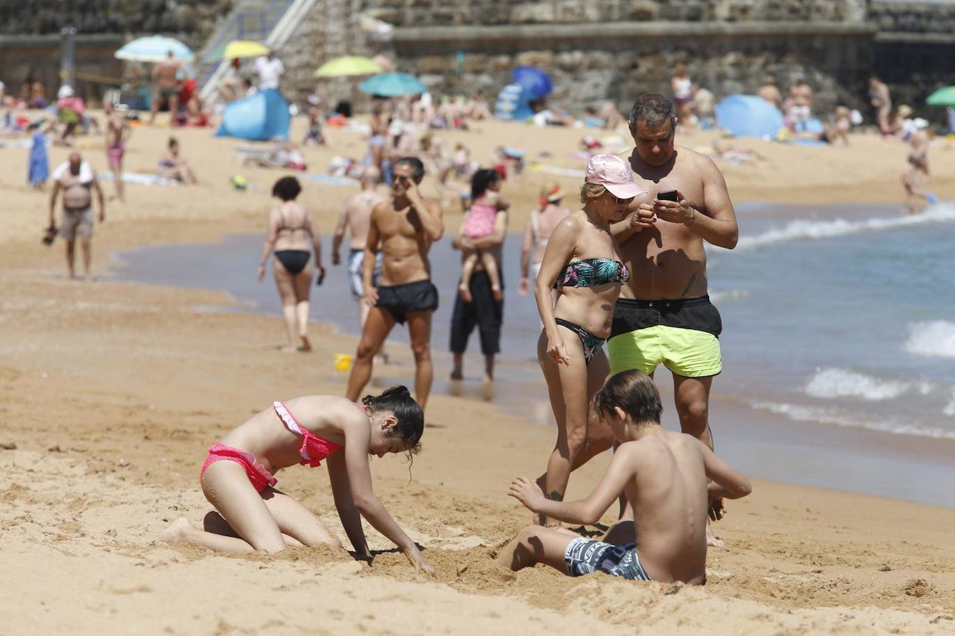 Aspecto que presentan este sábado las playas de El Sardinero y de la bahía de Santander, con muchos bañistas, gente paseando por la orilla, disfrutando del mar y tomando el sol.