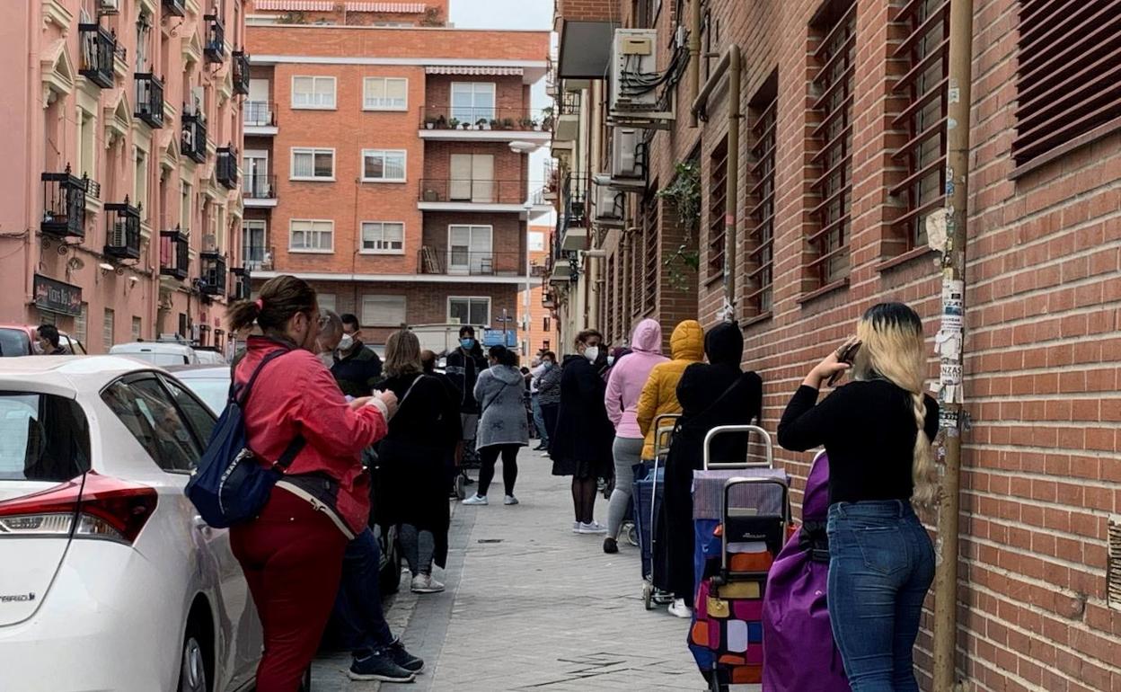 Ciudadanos esperando ante un economato de Cáritas. 